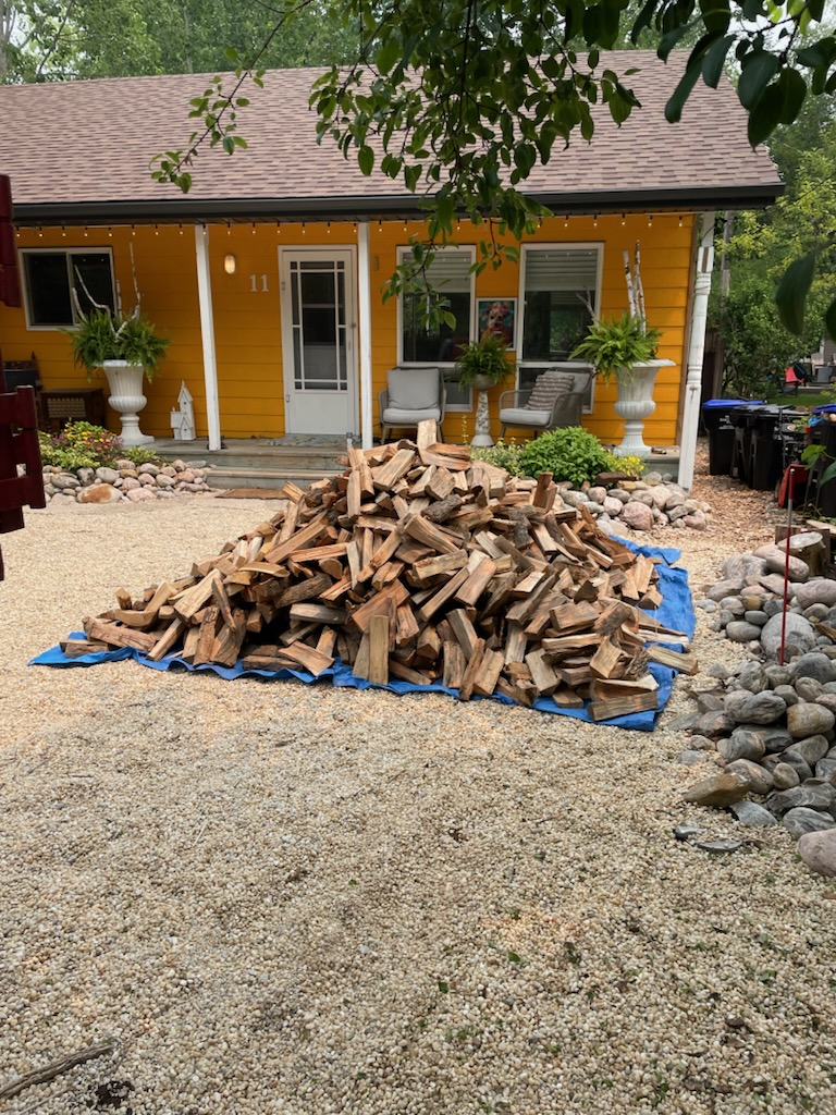 a pile of 8 - 12 inch firewood on a tarp in the driveway