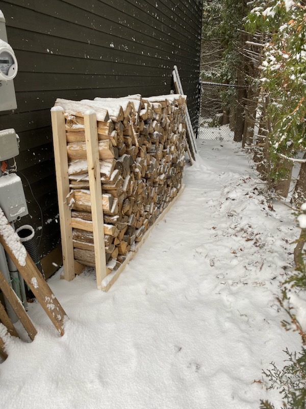 stacked firewood in a wood rack next to a house