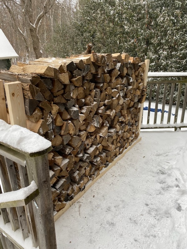 stacked firewood on a deck in a wooden rack