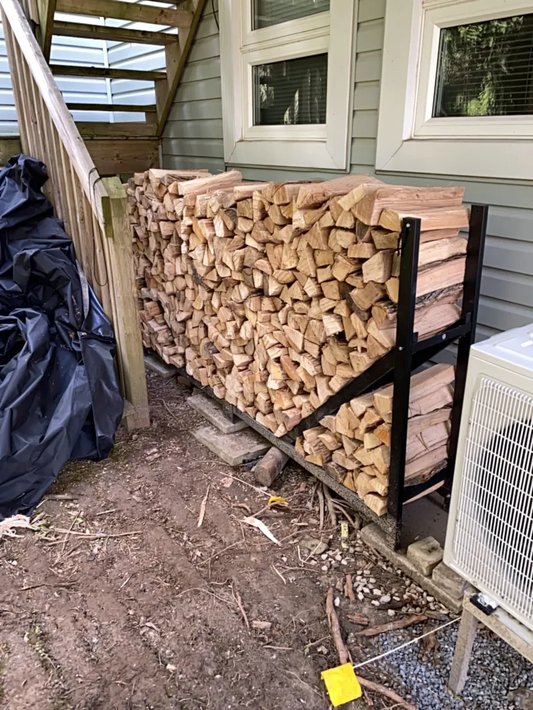 stacked firewood in a metal rack on a deck